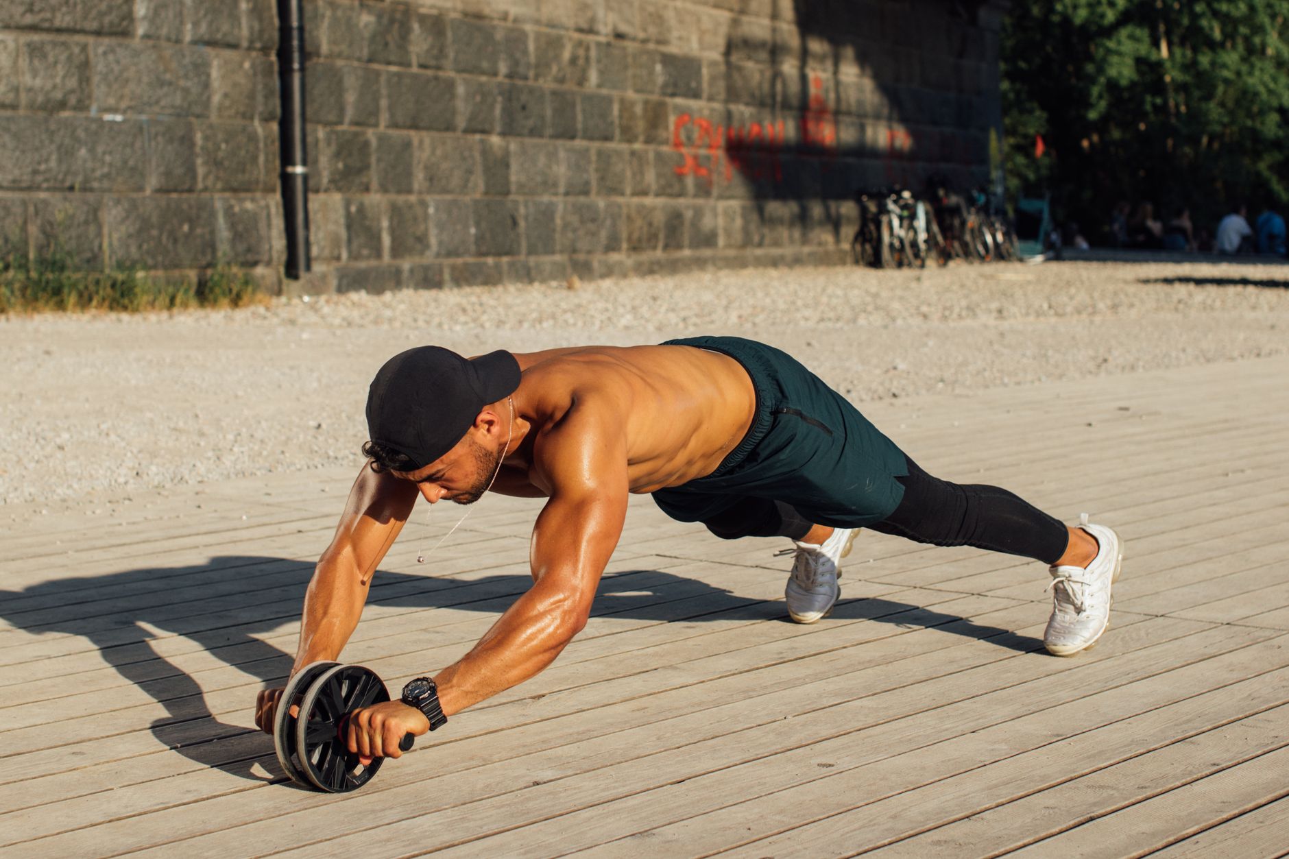 A person with strong core muscles demonstrating proper form while using an ab roller on a gym floor.