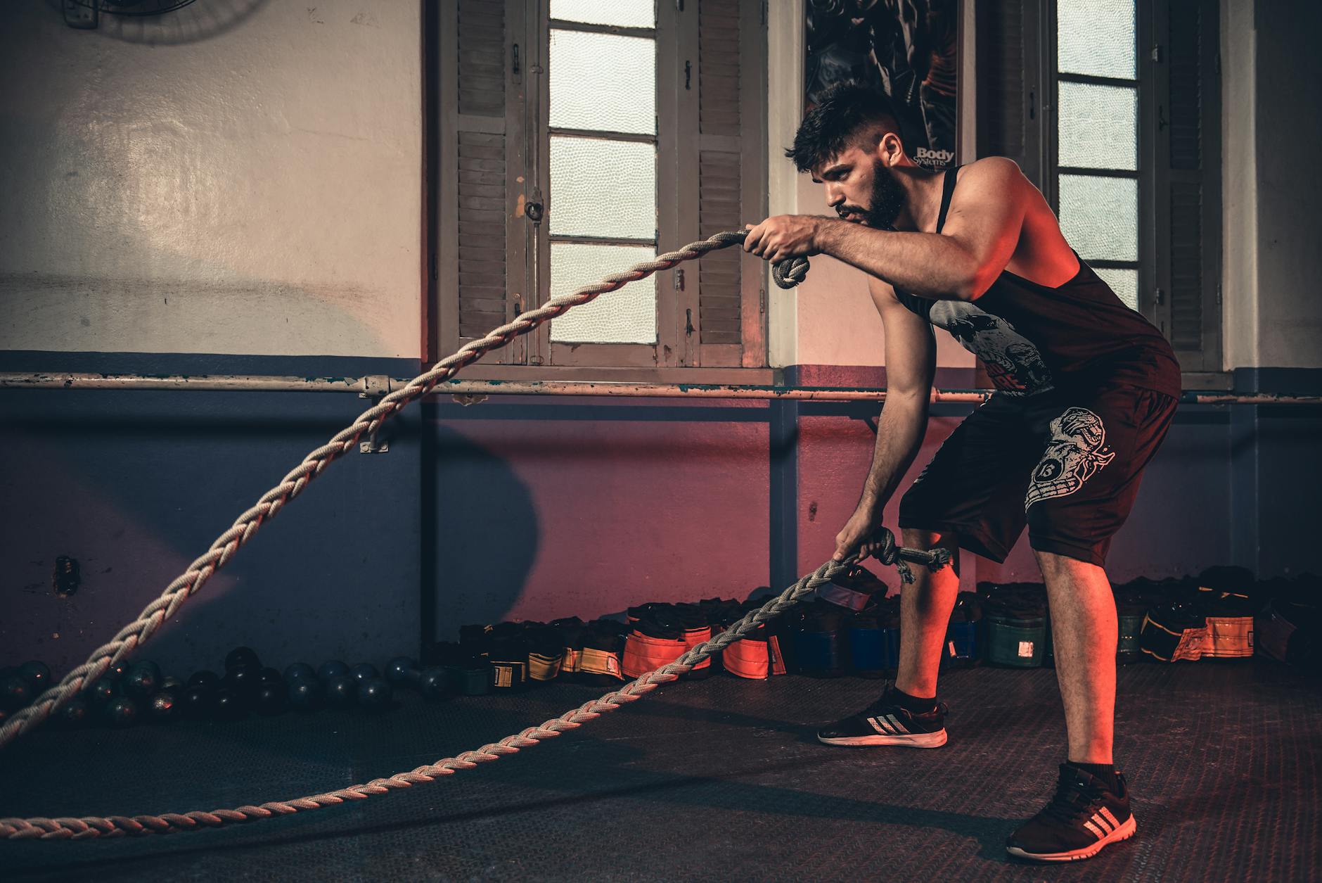 Man performing battle rope exercises in a home gym setting