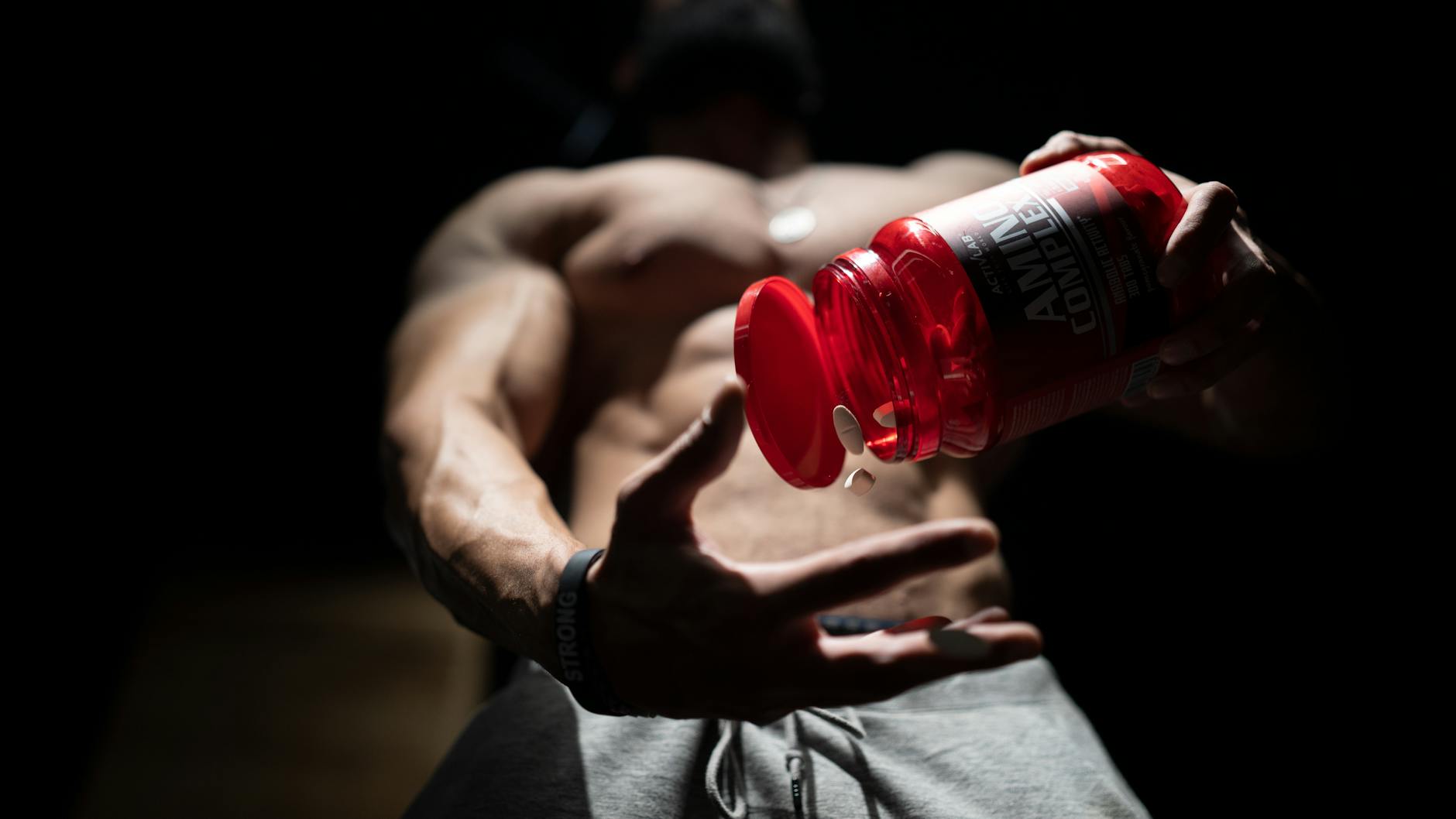 Variety of BCAA supplement powders and shaker bottles on a gym bench, representing top BCAA supplements for 2026.