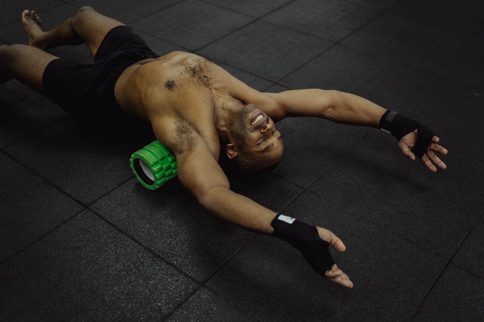 A person using a black foam roller on their leg