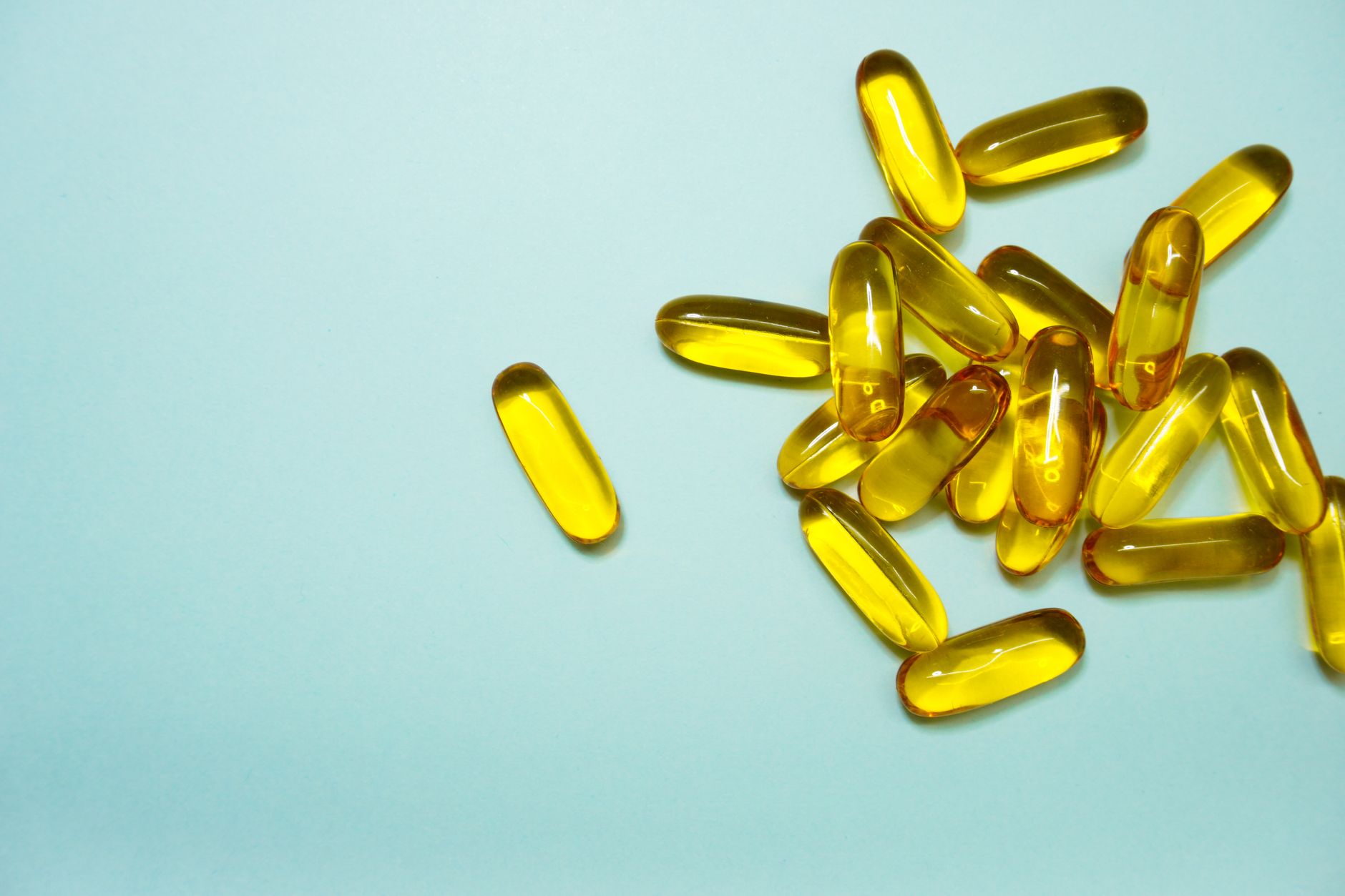 Variety of high-quality omega-3 fish oil supplements arranged on a dark gym background with weights and a shaker bottle