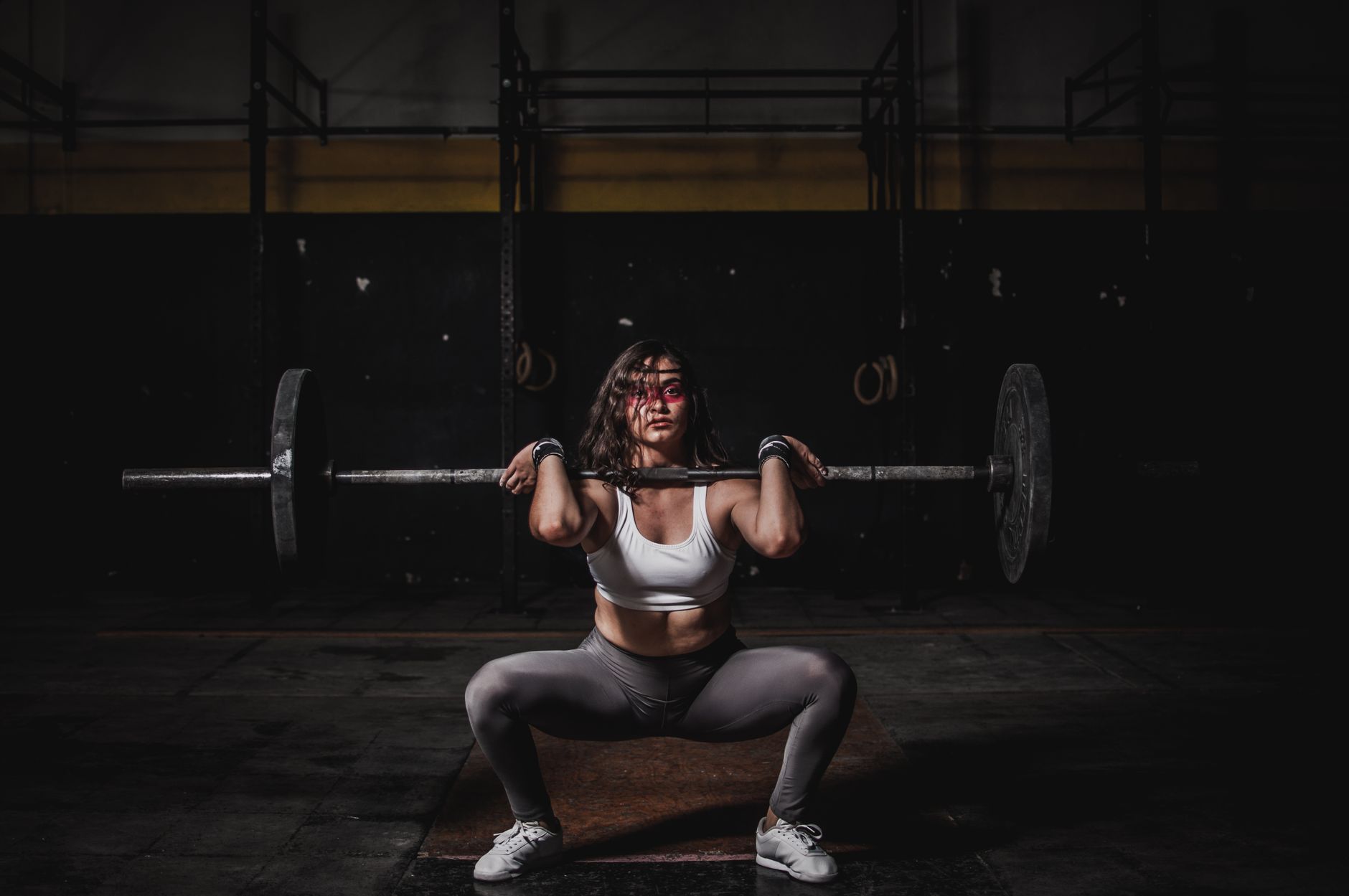Man performing a barbell back squat wearing weightlifting shoes in a home gym.