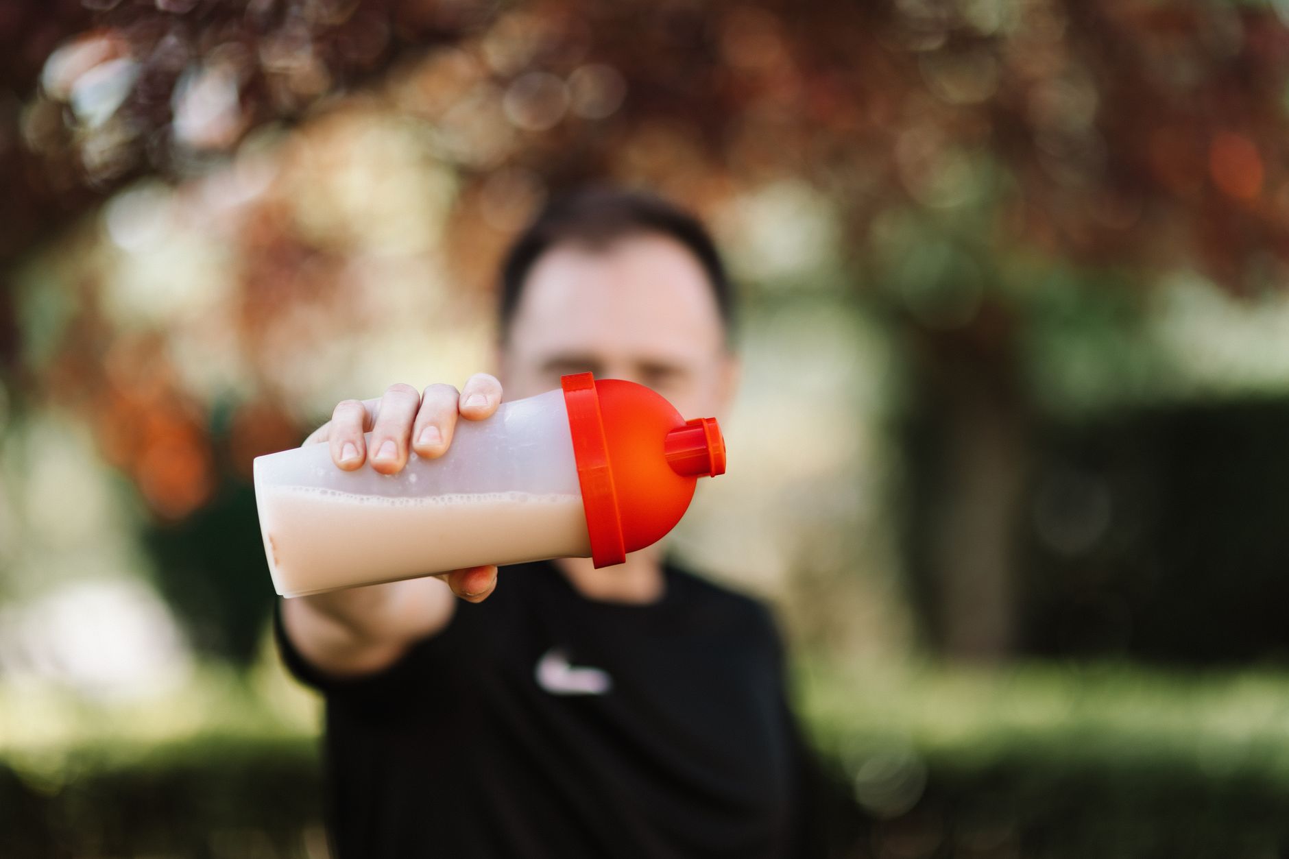 Man shaking a protein powder supplement in a shaker bottle after a workout, focusing on the best whey protein for muscle building in 2026.