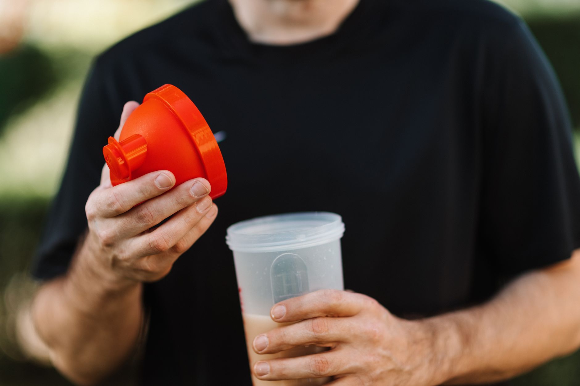 Man preparing a protein shake after a heavy lifting session, emphasizing optimal daily protein intake for muscle growth.