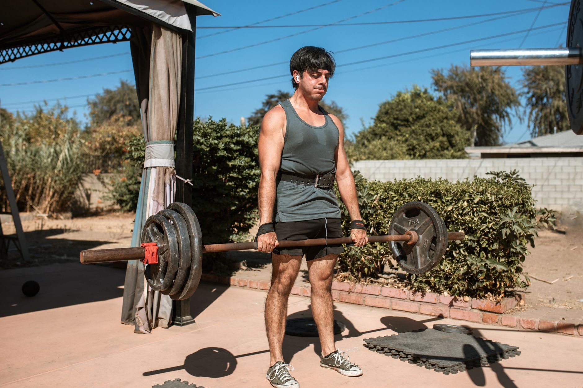 A heavy-duty leather lifting belt on a gym bench next to a barbell