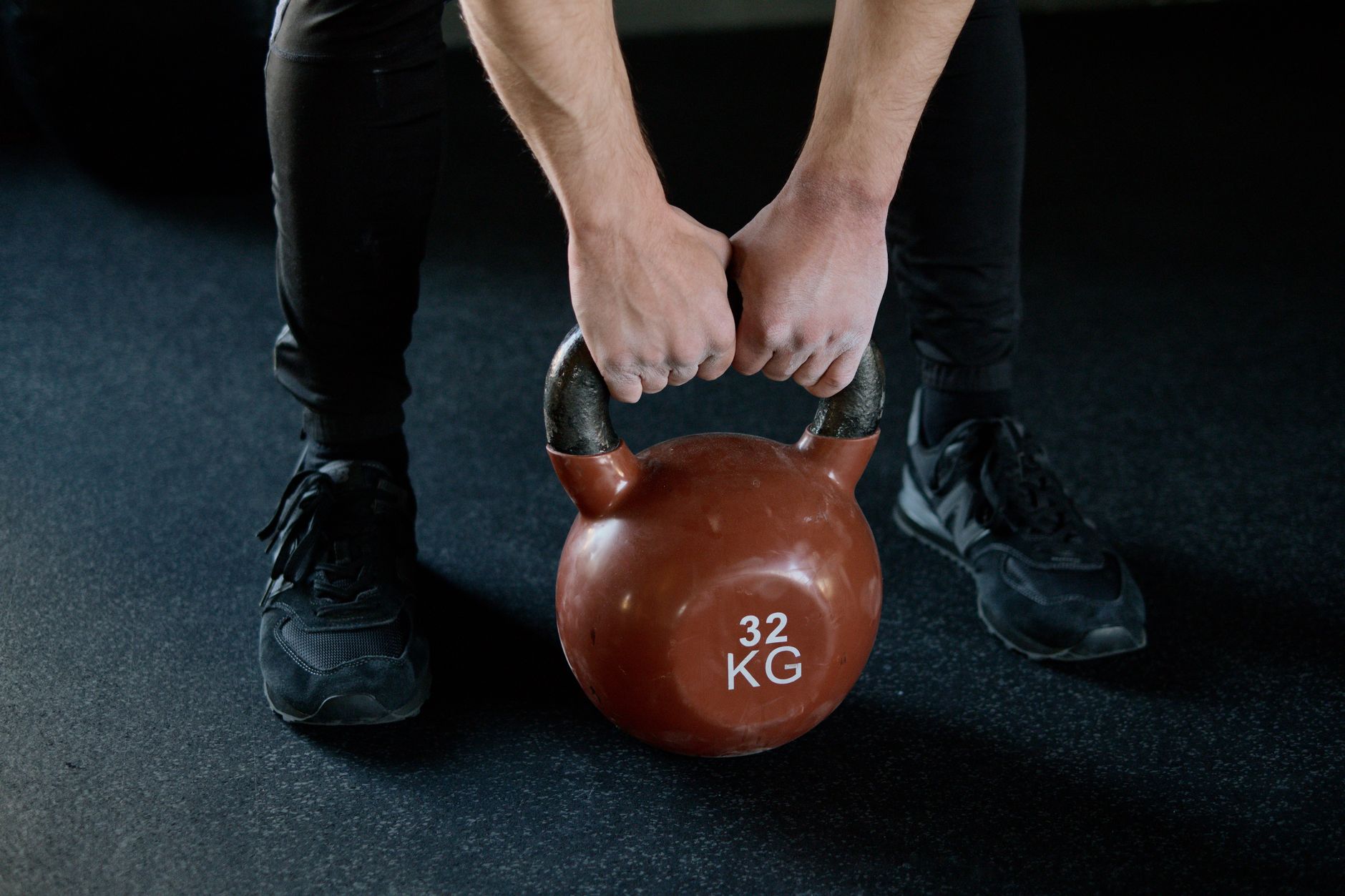 Man performing a kettlebell swing in an outdoor setting